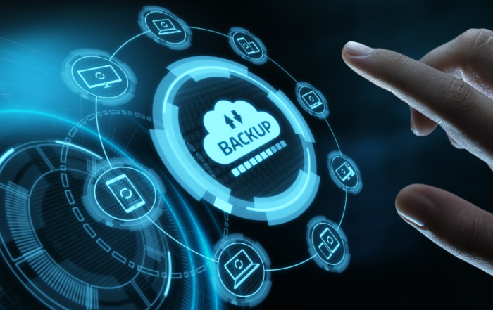 Conceptual image of a backup continuity plan a large hand attempts to press a backup button with icons of laptops, tablets, cell phones and more around it.