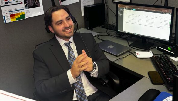 Andrew working service desk smiling in a tie
